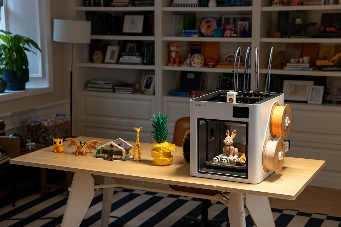 3D printer on a desk next to printed models